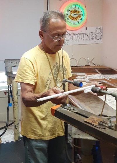 decorative image: Neon artist Al Littek bending glass to create a neon sign.